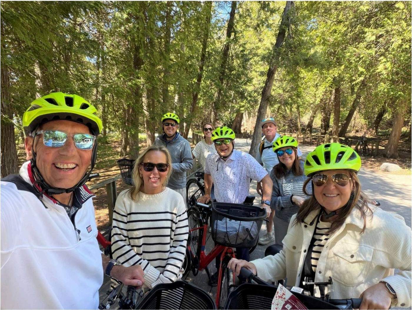 A group of cyclists in helmets and sunglasses posing for a selfie on a wooded trail ride