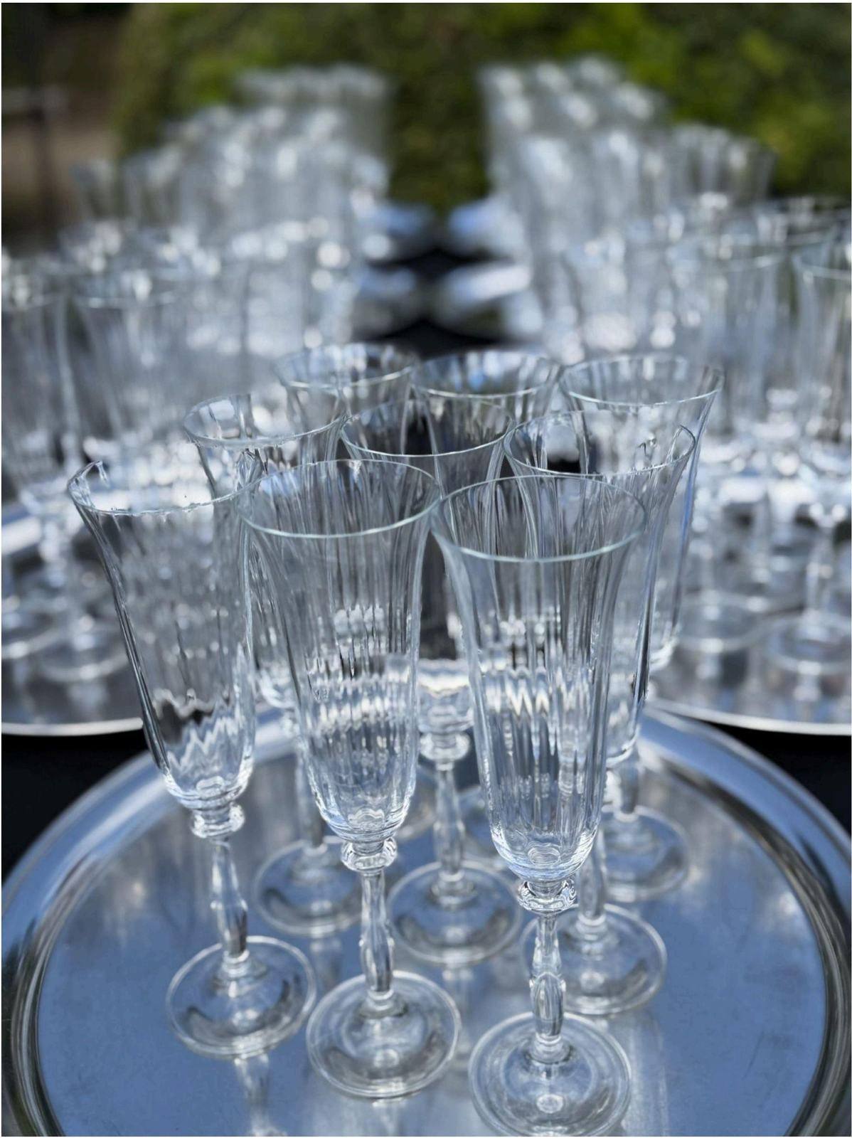 Empty fluted champagne glasses arranged on silver trays for a reception