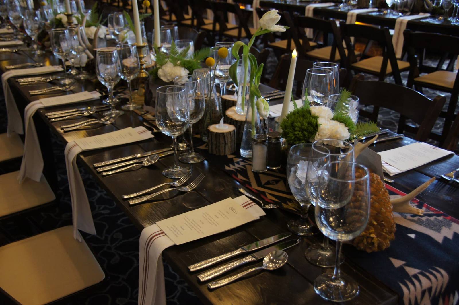 Elegant long table set with glassware, candles, white flowers and greenery for an Offsite Utah produced event