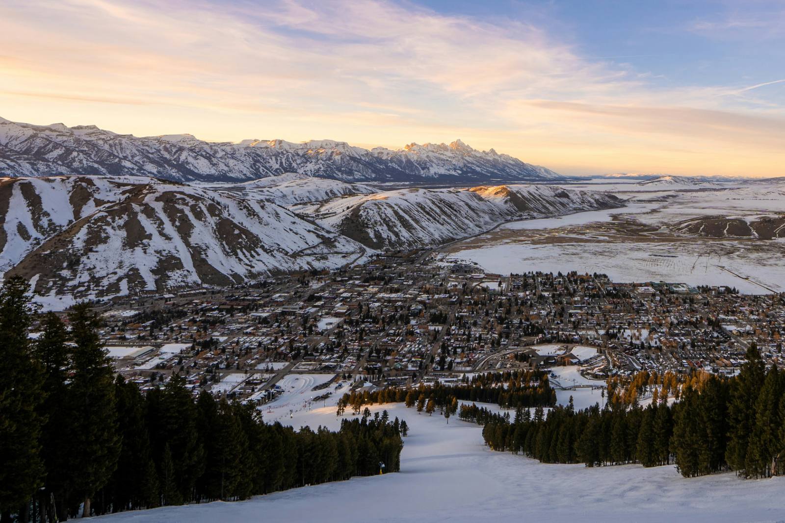 Aerial winter view of Jackson Hole, Wyoming with the snow-covered Teton Range and ski runs at golden hour