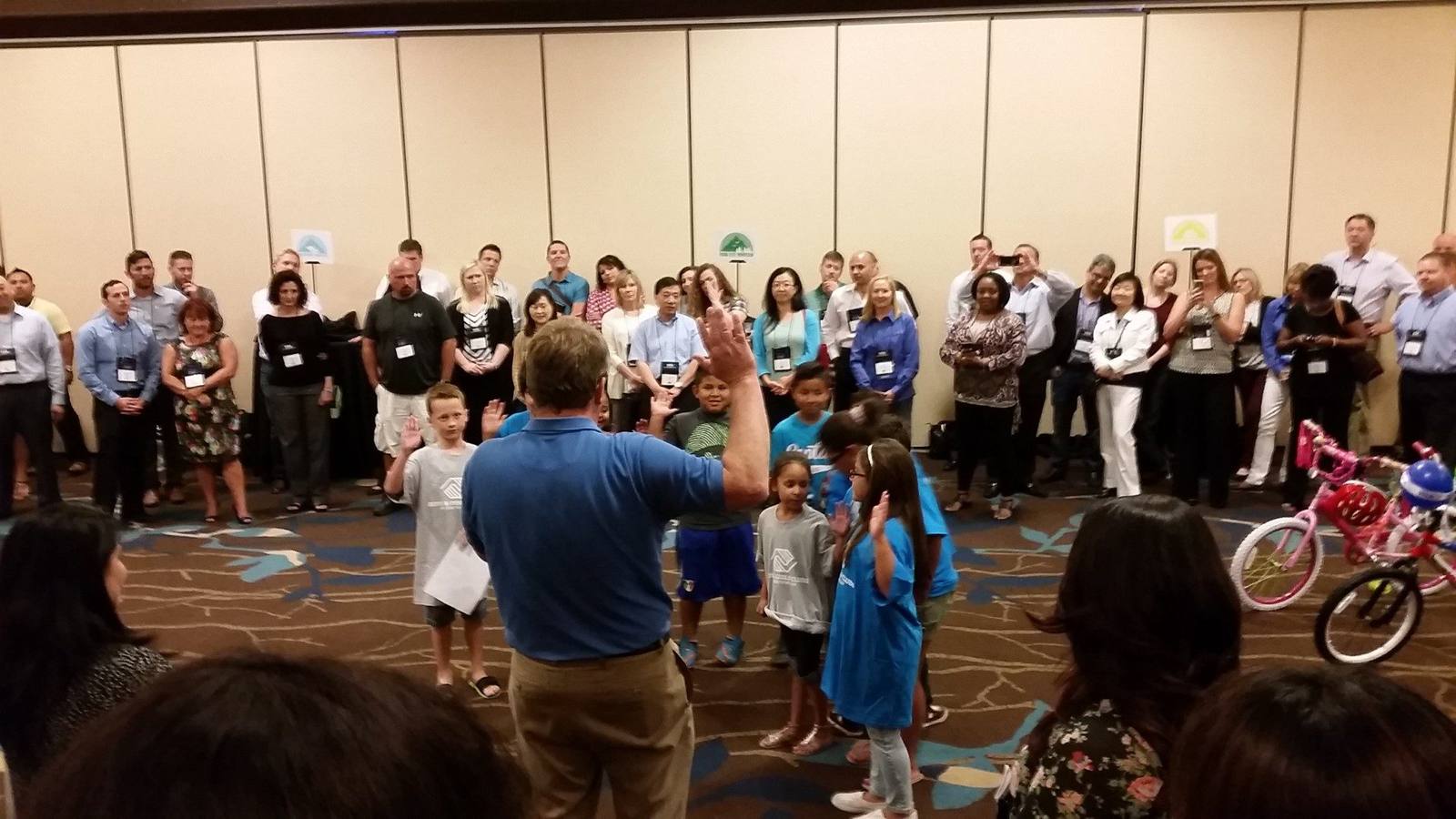 A corporate group gathered around children during a community service bike-building event